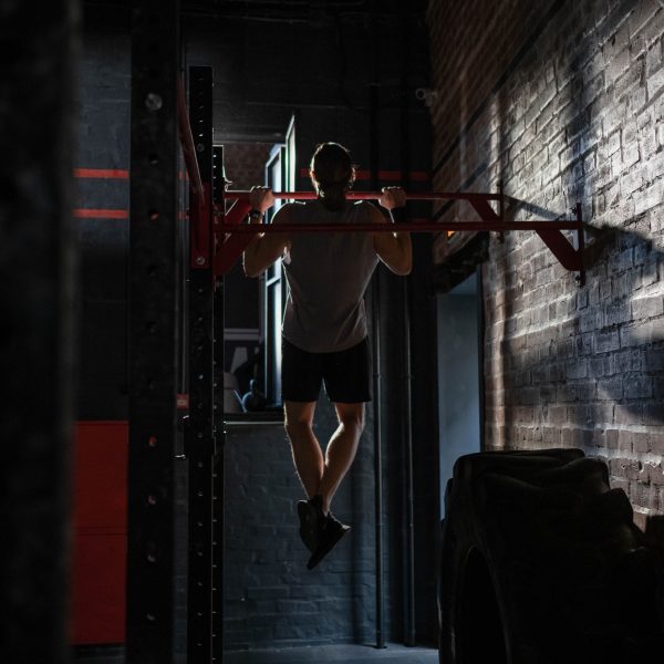 man doing pull ups inside of a dark gym