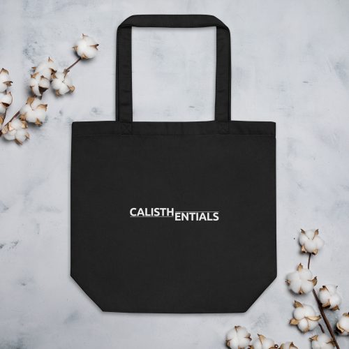 Black Calisthenics Tote Bag with white logo, laid flat with cotton flowers
